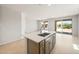 Open kitchen with an island, sink, neutral cabinets, tile flooring and sliding doors to the back yard at 26995 W Adam Ave, Buckeye, AZ 85396