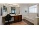 Bathroom features a vanity with a seated dressing table, a tub, and natural light at 10037 W Chipman Rd, Tolleson, AZ 85353