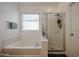 Bright bathroom featuring a soaking tub, separate glass-enclosed shower, and a window allowing natural light at 10037 W Chipman Rd, Tolleson, AZ 85353