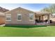 Home's backyard with low-maintenance synthetic grass, paver accents and a covered patio at 10454 W Maya Way, Peoria, AZ 85383