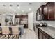 Charming kitchen with dark wood cabinets, granite counters, stainless appliances, and a spacious island with seating at 10454 W Maya Way, Peoria, AZ 85383