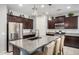 Beautiful kitchen with granite countertops, dark wood cabinetry, stainless steel appliances, and island with seating at 10454 W Maya Way, Peoria, AZ 85383