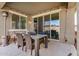 Relaxing covered patio featuring a glass table, stylish wicker chairs, and soft string lights for outdoor enjoyment at 10454 W Maya Way, Peoria, AZ 85383
