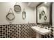 Unique powder room featuring decorative mirrors, pedestal sink, and striking tile pattern at 10596 E Yearling Dr, Scottsdale, AZ 85255