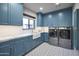 Stylish laundry room with blue cabinetry, a farmhouse sink, and modern washer and dryer units at 10596 E Yearling Dr, Scottsdale, AZ 85255