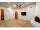 Living room featuring light wood flooring, white walls, stucco fireplace, tv and decorative wood doors at 10596 E Yearling Dr, Scottsdale, AZ 85255