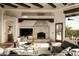 Cozy living room featuring a stone fireplace, beamed ceilings, and comfortable seating with an outdoor view at 10596 E Yearling Dr, Scottsdale, AZ 85255