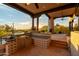 Outdoor kitchen featuring built-in grill, bar, and fireplace with sunset views in the desert community at 10596 E Yearling Dr, Scottsdale, AZ 85255