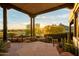 Covered outdoor patio featuring stone flooring, desert landscaping, and golf course views at 10596 E Yearling Dr, Scottsdale, AZ 85255