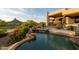 Stunning pool area with rock waterfall feature, lush landscaping, and desert mountain views in this desert oasis at 10596 E Yearling Dr, Scottsdale, AZ 85255