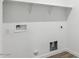 A well-lit laundry room with a shelf, electric outlets, and necessary hookups at 12443 E Bahia Ct, Florence, AZ 85132