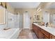 Well-lit bathroom featuring a soaking tub, a separate glass-enclosed shower, and dual sinks at 14694 W Mandalay Ln, Surprise, AZ 85379