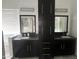 Modern bathroom featuring dual sinks, sleek black cabinets, and well-lit mirrors at 15691 N 104Th Pl, Scottsdale, AZ 85255
