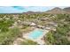 Aerial view of a community pool, hot tub, and clubhouse with mountain views in a desert landscape at 15691 N 104Th Pl, Scottsdale, AZ 85255