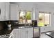 Kitchen features white cabinetry, dark countertops, and a stainless steel dishwasher at 15691 N 104Th Pl, Scottsdale, AZ 85255