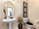 Stylish powder room featuring a modern pedestal sink, neutral tones, and decorative accents at 17613 W Gelding Dr, Surprise, AZ 85388