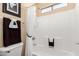 Close-up view of the bathroom's tiled tub-shower with a white shower curtain at 17613 W Gelding Dr, Surprise, AZ 85388