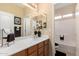 Well-lit bathroom with wood vanity, white countertop, and decorative accents, plus combined shower-tub at 17613 W Gelding Dr, Surprise, AZ 85388