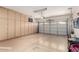 Large garage with ample storage cabinets, a rolling door, and epoxy flooring at 17613 W Gelding Dr, Surprise, AZ 85388