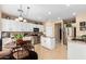 Open kitchen has stainless appliances, granite countertops, eat in table, island with sink, and white cabinets at 17613 W Gelding Dr, Surprise, AZ 85388