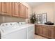 Spacious laundry room featuring a side-by-side washer and dryer and wooden cabinets above at 17613 W Gelding Dr, Surprise, AZ 85388