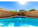 A cool swimming pool with a baja shelf and tranquil waterfall feature, set in a private backyard at 17613 W Gelding Dr, Surprise, AZ 85388