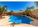 Backyard oasis with a pristine swimming pool, rock waterfall, and mature palm trees at 17613 W Gelding Dr, Surprise, AZ 85388