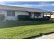 Well-maintained front yard featuring lush green grass, mature landscaping, and a covered porch with outdoor seating at 19046 N Signal Butte Cir, Sun City, AZ 85373