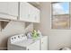 Bright laundry room featuring white washer and dryer and white cabinets with convenient shelving, bathed in natural light at 19305 E Oriole Way, Queen Creek, AZ 85142