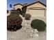 Inviting front yard showcasing an American flag, gravel landscaping, and thriving flowering bushes with an arched entryway at 2132 W Gold Dust Ave, San Tan Valley, AZ 85144