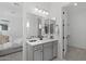 Bright bathroom with gray cabinets, dual sinks, decorative mirrors, and modern lighting fixtures at 2149 W Rowel Rd, Phoenix, AZ 85085
