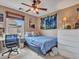 Cozy bedroom with a ceiling fan, a large window, and a bed with floral bedding, paired with a white dresser and desk at 2307 E Pecan Rd, Phoenix, AZ 85040