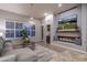 Living room featuring a fireplace, mounted TV, modern chandelier, and large windows with shutters at 33601 N 64Th St, Scottsdale, AZ 85266
