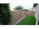 Backyard with artificial grass, a tall block wall, and ambient string lighting overhead at 4090 S Virginia Way, Chandler, AZ 85249