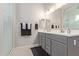 Bathroom features a double sink vanity with modern fixtures, gray cabinets, black and white patterned rug and glass enclosed shower at 4090 S Virginia Way, Chandler, AZ 85249