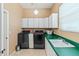 Practical laundry room equipped with modern washer and dryer, ample cabinet space, and a utility sink for convenience at 521 E Horseshoe Ave, Gilbert, AZ 85296