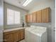Bright laundry room featuring built-in cabinets, countertop space, and modern white washer and dryer units at 5289 S Red Yucca Ln, Gold Canyon, AZ 85118
