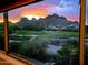 Mountain range with colorful sunset viewed from a window, showcasing a golf course and houses at 5370 S Desert Dawn Dr # 30, Gold Canyon, AZ 85118