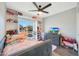 Bright bedroom with a fan, grey bed, and built in shelving filled with stuffed animals at 6029 W Pershing Ave, Glendale, AZ 85304