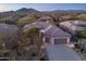 Aerial view of home, highlighting desert landscaping, three-car garage, and barrel tile roof, with mountain backdrop at 6888 E Mighty Saguaro Way, Scottsdale, AZ 85266