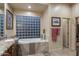Luxurious bathroom featuring a soaking tub, glass block window, and walk-in closet access at 6888 E Mighty Saguaro Way, Scottsdale, AZ 85266