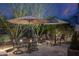 Outdoor patio with ambient lighting, stone pavers, two tables with chairs and umbrellas, perfect for entertaining at night at 6888 E Mighty Saguaro Way, Scottsdale, AZ 85266