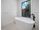 Bright bathroom with a modern soaking tub, black fixtures and a picture window with landscaping views at 7528 E Windrose Dr, Scottsdale, AZ 85260