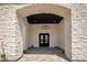 Grand entrance featuring stone archway, black double doors, and decorative chandelier at 7528 E Windrose Dr, Scottsdale, AZ 85260