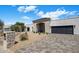 Modern house exterior with desert landscaping, stone accents, and black garage door at 7528 E Windrose Dr, Scottsdale, AZ 85260
