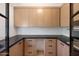 Butler's pantry with wood cabinets, black countertop, and stainless steel oven at 7528 E Windrose Dr, Scottsdale, AZ 85260