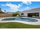 Relaxing backyard with a refreshing pool, lush lawn, and built-in barbecue area at 7528 E Windrose Dr, Scottsdale, AZ 85260