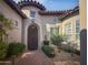 Charming arched entrance to a home with a secure wrought iron door, lush landscaping, and brick paver walkway at 8964 E Mountain Spring Rd, Scottsdale, AZ 85255