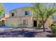 A tan two-story home with well-maintained landscaping and a two-car garage is seen on a sunny day at 9541 W Frank Ave, Peoria, AZ 85382