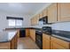 Kitchen with wood cabinetry, granite countertops, black appliances, and a window above the sink at 9541 W Frank Ave, Peoria, AZ 85382
